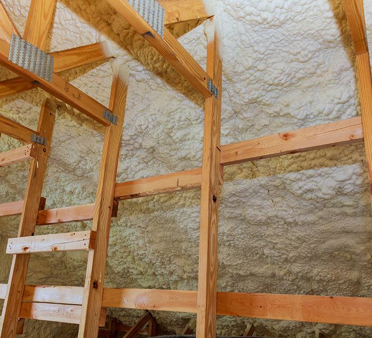 Loft space before spray foam insulation removal, showing foam applied to roof rafters